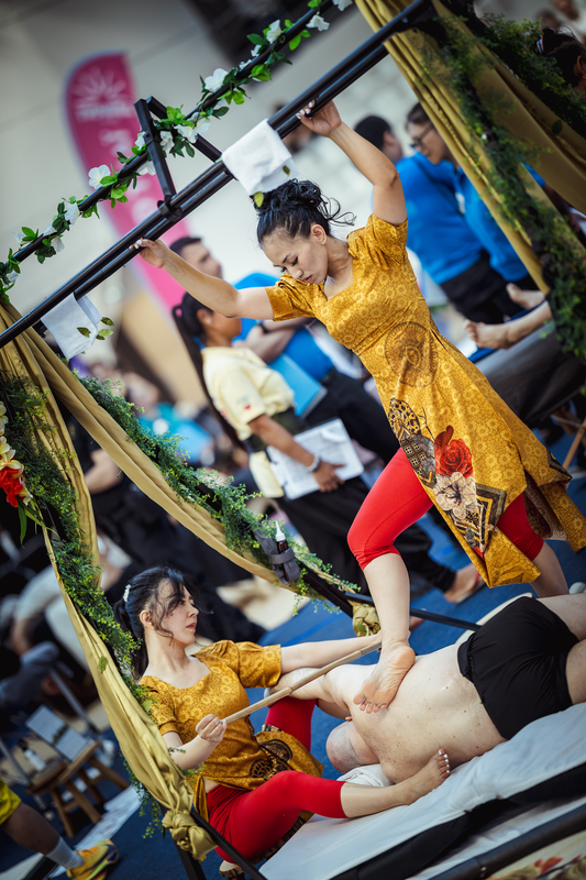 Dr Amanda (seated) and Lynn (standing) massaging right side of male client